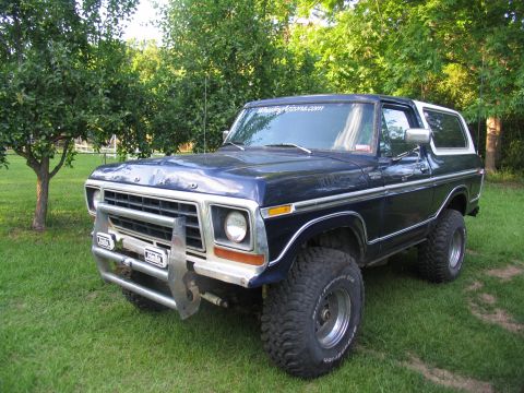 1995 Ford C-350 (Centurion Conversions) - This blue Ford Bronco features off-road tires and a custom brush guard, suggesting it's built for terrain.