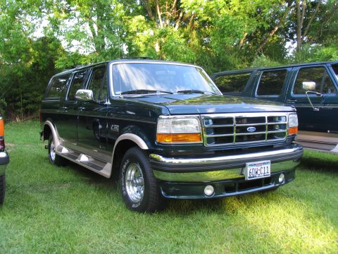 1995 Ford C-350 (Centurion Conversions) - A dark green Ford Bronco SUV conversion is parked on a grassy lawn next to another similar vehicle.
