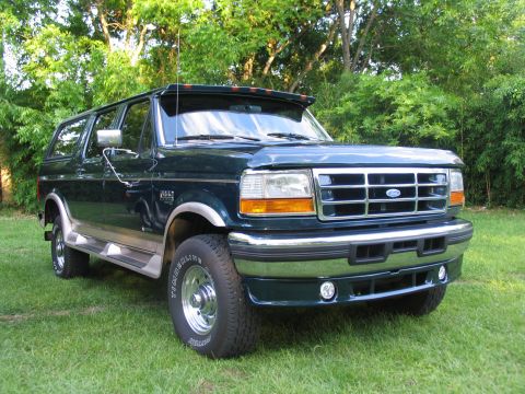 1995 Ford C-350 (Centurion Conversions) - A dark green 1995 Ford C-350 Centurion Conversions SUV is parked on a grassy lawn with trees in the background.