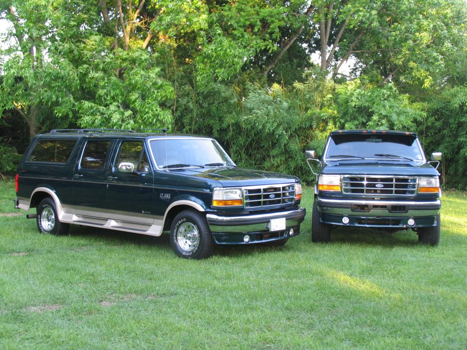 1995 Ford C-350 (Centurion Conversions) and another Ford SUV parked on grass with trees in background