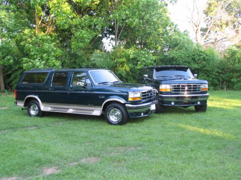 1995 Ford C-350 (Centurion Conversions) - Two Ford SUVs are parked on a grassy lawn with trees in the background.