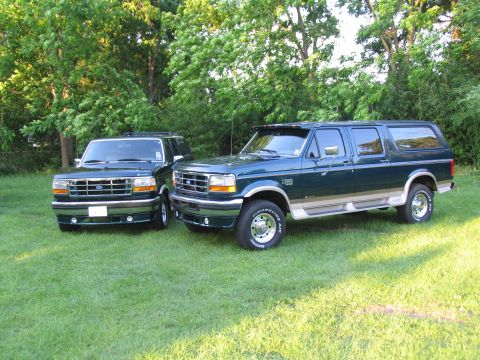 1995 Ford C-350 (Centurion Conversions) - Two Ford SUVs, a 1995 Centurion conversion and a Bronco, sit on a grassy lawn with trees in the background.