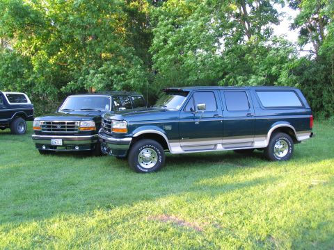 1995 Ford C-350 (Centurion Conversions) - Two Ford SUVs are parked on a grassy lawn with trees in the background.