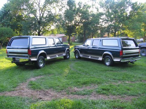1995 Ford C-350 (Centurion Conversions) - Two Ford Bronco Centurions are parked on a grassy lawn with trees in the background.