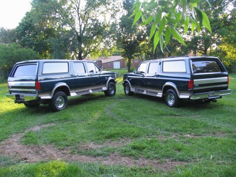 1995 Ford C-350 (Centurion Conversions) - Two dark green Ford Bronco Centurion conversions with tan trim are parked on a grassy lawn.