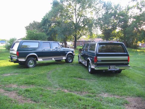 1995 Ford C-350 (Centurion Conversions) - Two Ford SUVs, likely from the mid-1990s, are parked side-by-side on a sunny day.