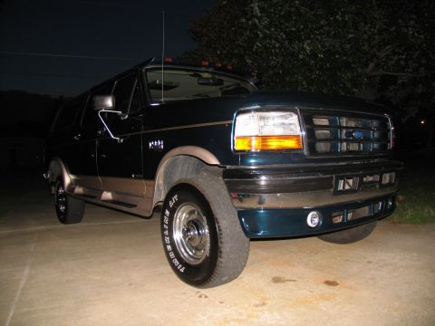1995 Ford C-350 (Centurion Conversions) - This Ford Bronco features a two-tone paint scheme and sits parked on a concrete driveway under a tree.