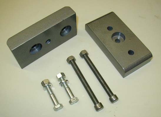 Two metal lift blocks and four bolts on a white surface