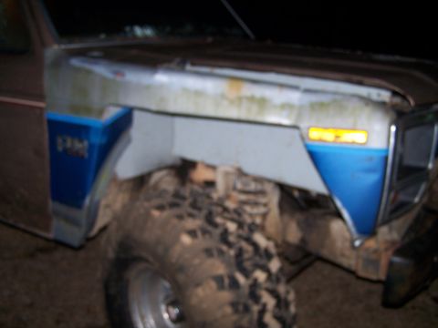 1981 Ford Bronco - A brown and blue Ford Bronco's front fender and mud-caked tire are visible.
