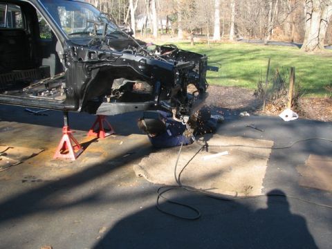 1994 Toyota Tacoma - Welder repairs the front section of a truck chassis, which is elevated on jack stands.