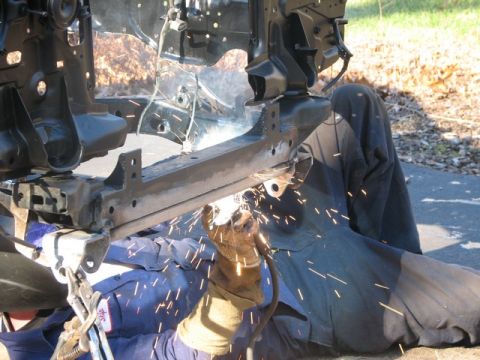 1994 Toyota Tacoma - A person is welding the frame of a vehicle, with many sparks flying from the weld.