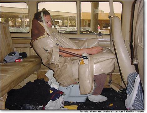 1971 Ford Ranchero - Man sits in a makeshift seat inside a van, surrounded by personal belongings and debris.