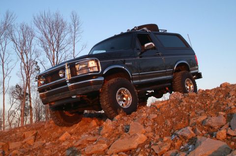 1995 Ford Bronco - 1995 Ford Bronco navigating a steep, rocky incline under a clear sky.