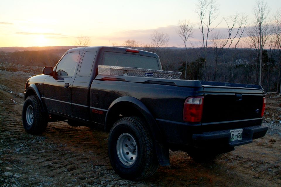 Dark Ford Ranger Edge extended-cab pickup at sunset with diamond-plate bed toolbox