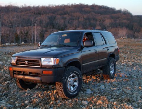 1995 Ford Bronco - Toyota 4Runner parked on rocky ground with trees in the background.