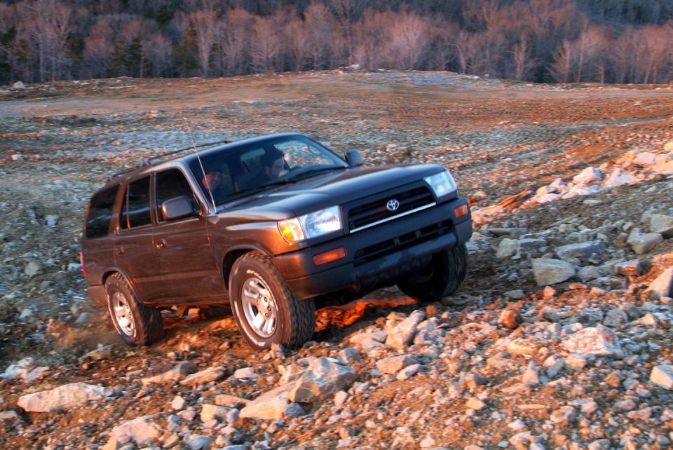 Dark SUV driving on a rocky, uneven terrain