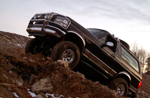 1995 Ford Bronco - A black Ford Bronco navigates a steep dirt incline, its off-road capabilities.
