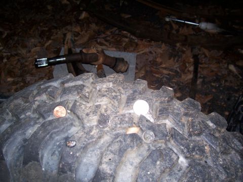 1985 Ford Bronco - Coins are placed on the tire tread, with a driveshaft assembly in the background.