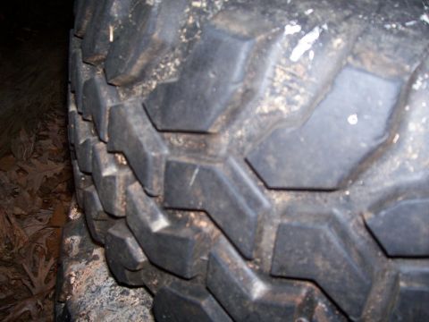 1985 Ford Bronco - A close-up shows the aggressive tread pattern of a mud terrain tire, covered in dirt.