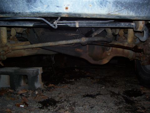 1985 Ford Bronco - The undercarriage of a vehicle is shown, a D44 TTB axle and rusty suspension parts.