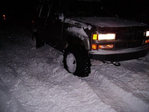 2000 Chevrolet Tahoe - A dark 2000 Chevrolet Tahoe is stuck in deep snow, with its front tires partially buried.