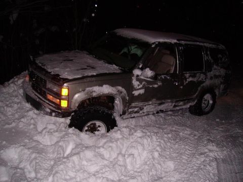 2000 Chevrolet Tahoe - This SUV appears to be stuck in a snowdrift, with its front wheel deep in the snow.