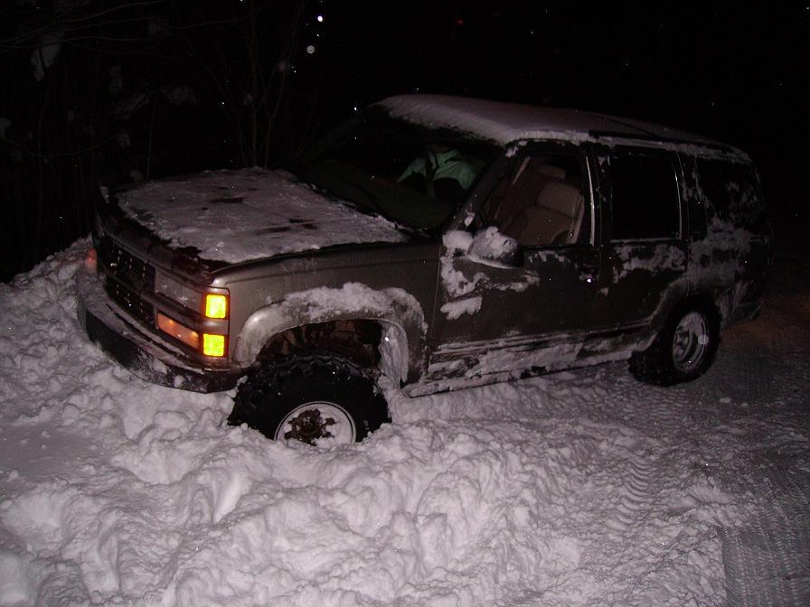 Brown SUV stuck in deep snow, front wheel submerged
