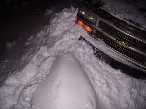 2000 Chevrolet Tahoe - This Chevrolet truck is stuck deep in a snowdrift, with only the front grille and headlight visible.