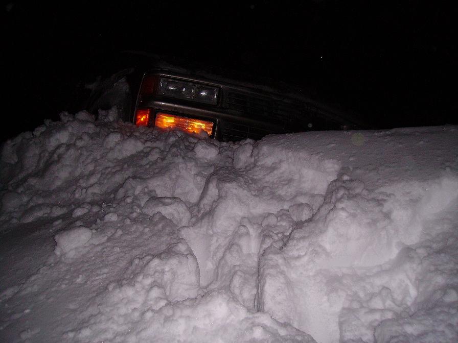 2000 Chevrolet Tahoe stuck in deep snow, front end visible with headlights on