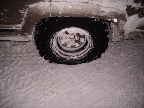 2000 Chevrolet Tahoe - A vehicle's tire is partially buried in snow, showing tire tracks in the snow.