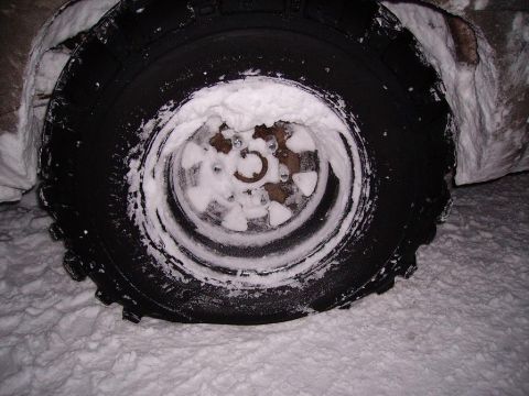 2000 Chevrolet Tahoe - A close-up view of a vehicle's tire and wheel, partially obscured by snow.