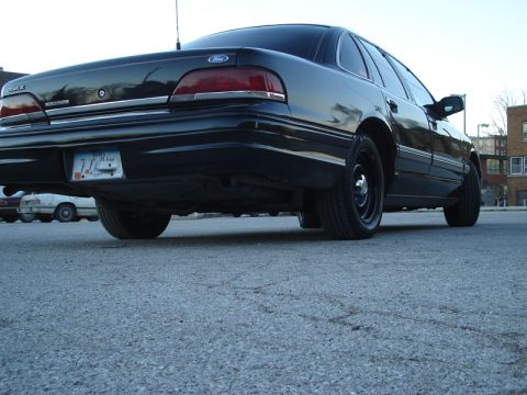 1992 Ford Crown Victoria - The rear passenger side of a black 1992 Ford Crown Victoria is shown from a low angle.