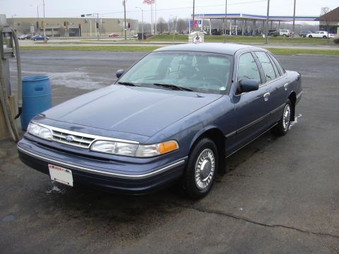1996 Ford Crown Victoria - Blue 1996 Ford Crown Victoria sedan parked on a wet asphalt surface.