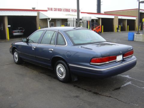 1996 Ford Crown Victoria - A blue sedan is parked outside a 24-hour car wash and storage facility.