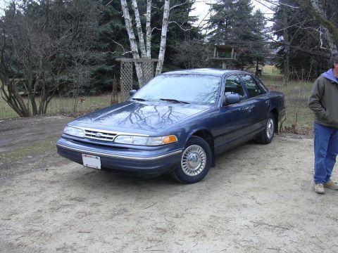 1996 Ford Crown Victoria - A dark blue 1995 Ford Crown Victoria sedan is parked outdoors in a dirt lot.