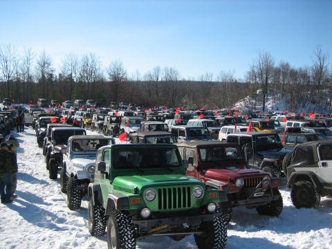2002 Jeep Wrangler - A large group of Jeep Wranglers are parked in a snowy field under a clear blue sky.