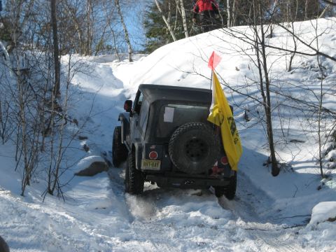 2002 Jeep Wrangler - A black 2002 Jeep Wrangler navigates a snowy off-road trail, kicking up snow as it goes.