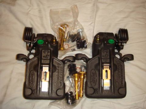 1993 Ford Taurus - Pair of Ford brake calipers and associated hardware are displayed on a white surface.