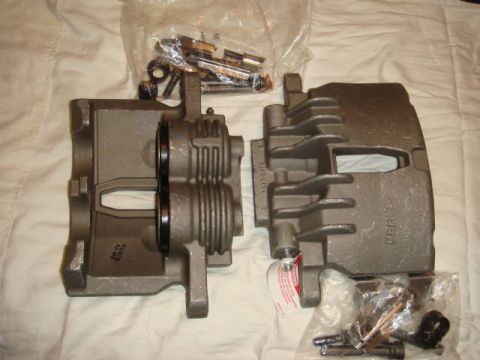 1993 Ford Taurus - Brake calipers and associated hardware are laid out on a white, textured surface.