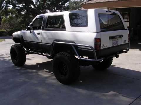 1985 Toyota 4Runner - Modified white Toyota 4Runner with aftermarket roll cage and oversized tires is parked on a driveway.