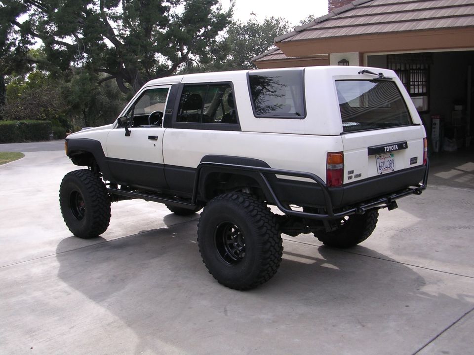 White 1985 Toyota 4Runner with large tires and off-road bumper, rear 3/4 view