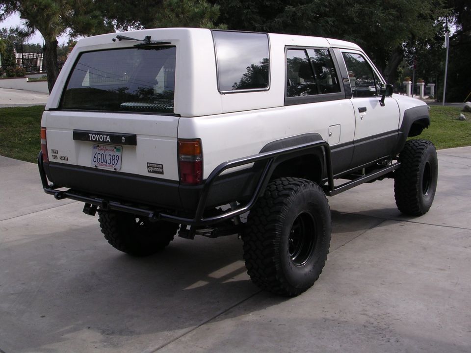 1985 Toyota 4Runner with aftermarket bumpers and large off-road tires, viewed from the rear