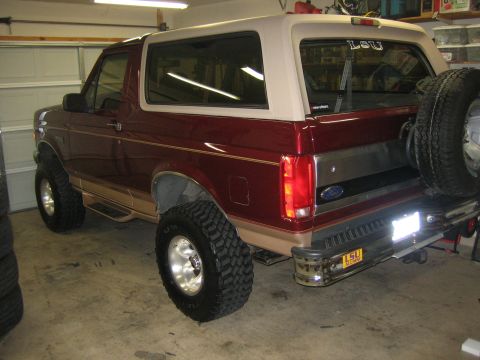 1996 Ford Bronco - This maroon 1996 Ford Bronco features tan trim, a spare tire mounted on the rear, and an LSU sticker on the back window.