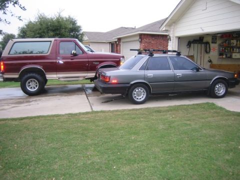1996 Ford Bronco - A maroon Ford Bronco is parked next to a grey sedan in a driveway.