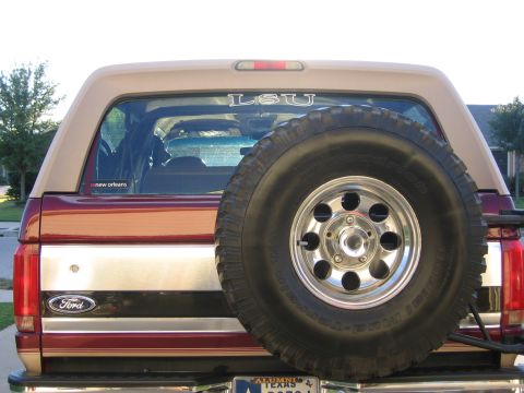 1996 Ford Bronco - Rear view of a maroon and tan Ford Bronco, a spare tire and various stickers on the rear window.