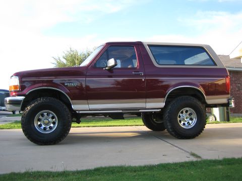 1996 Ford Bronco - Side view of a lifted 1996 Ford Bronco with a two-tone paint job and aftermarket wheels.