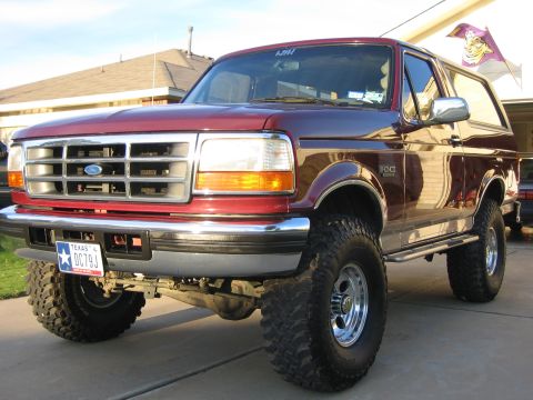 1996 Ford Bronco - This maroon Ford Bronco features a lifted suspension and aggressive off-road tires, indicating a modified build.