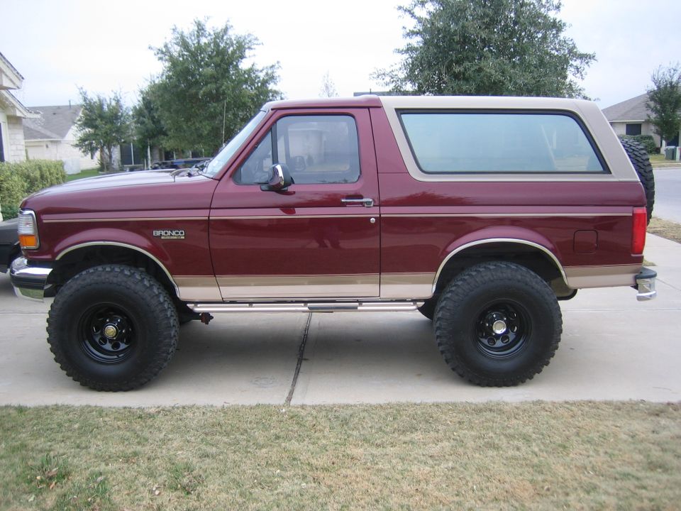 Maroon and tan 1996 Ford Bronco side view with lifted suspension and off-road tires