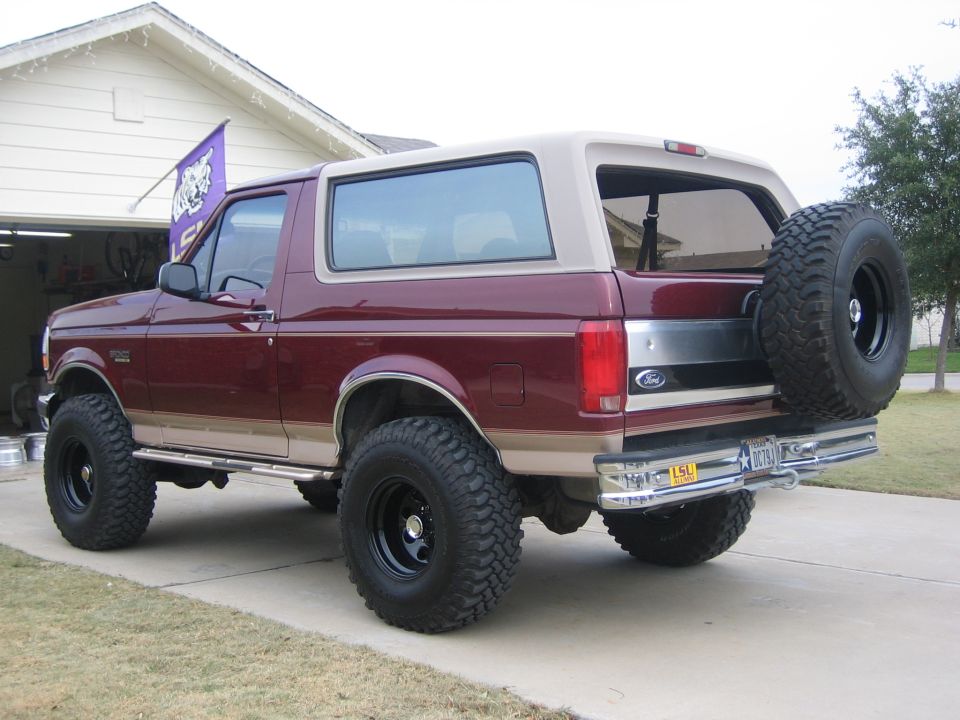 1996 Ford Bronco, maroon with tan top, lifted with large tires, spare tire mounted on rear door