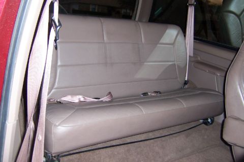 1996 Ford Bronco - Interior view of a vehicle's rear bench seat, showing tan upholstery and seatbelts.
